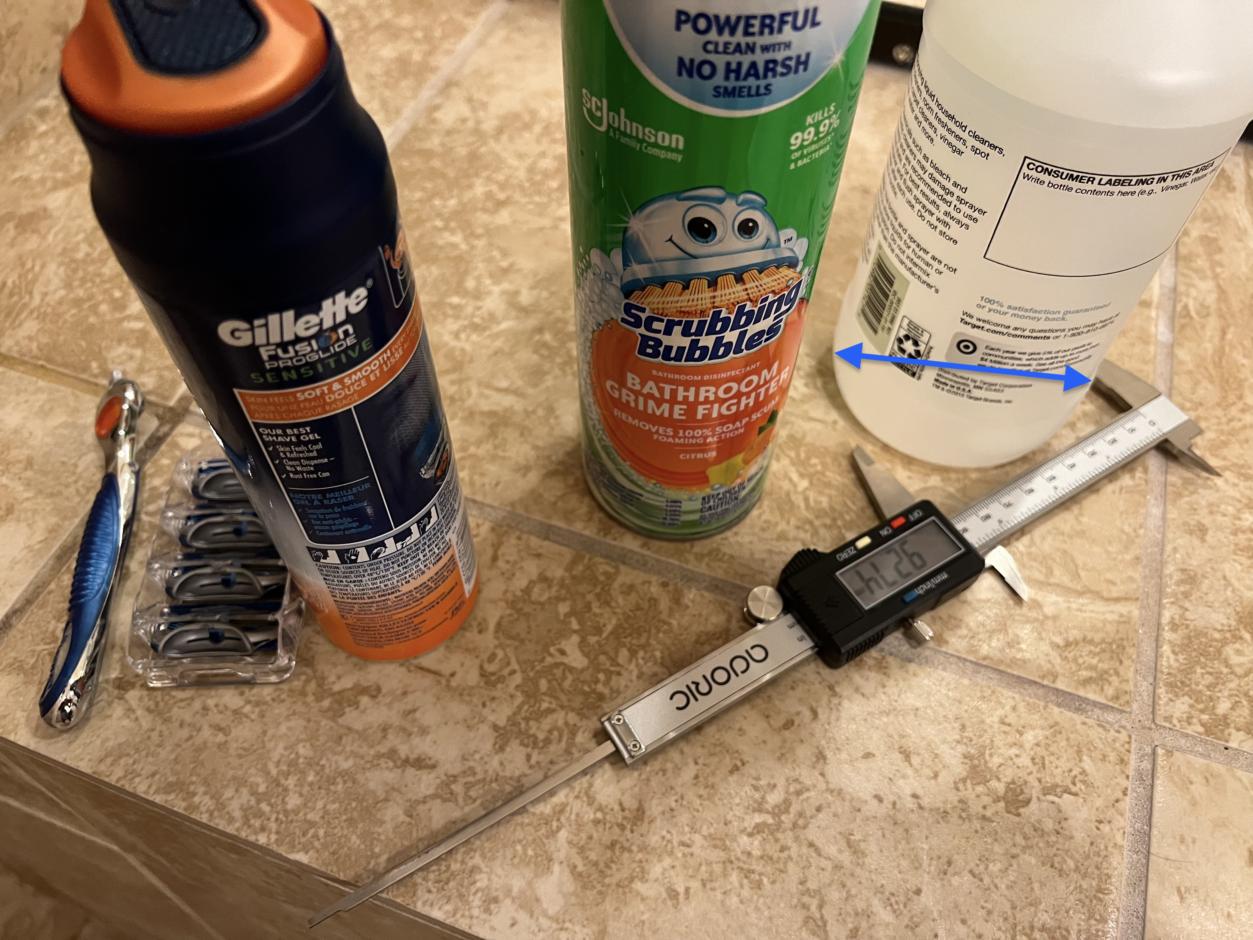 Photograph of measurements of shower accessories with cylindrical forms including spray bottle foaming cleaner and shaving accessories